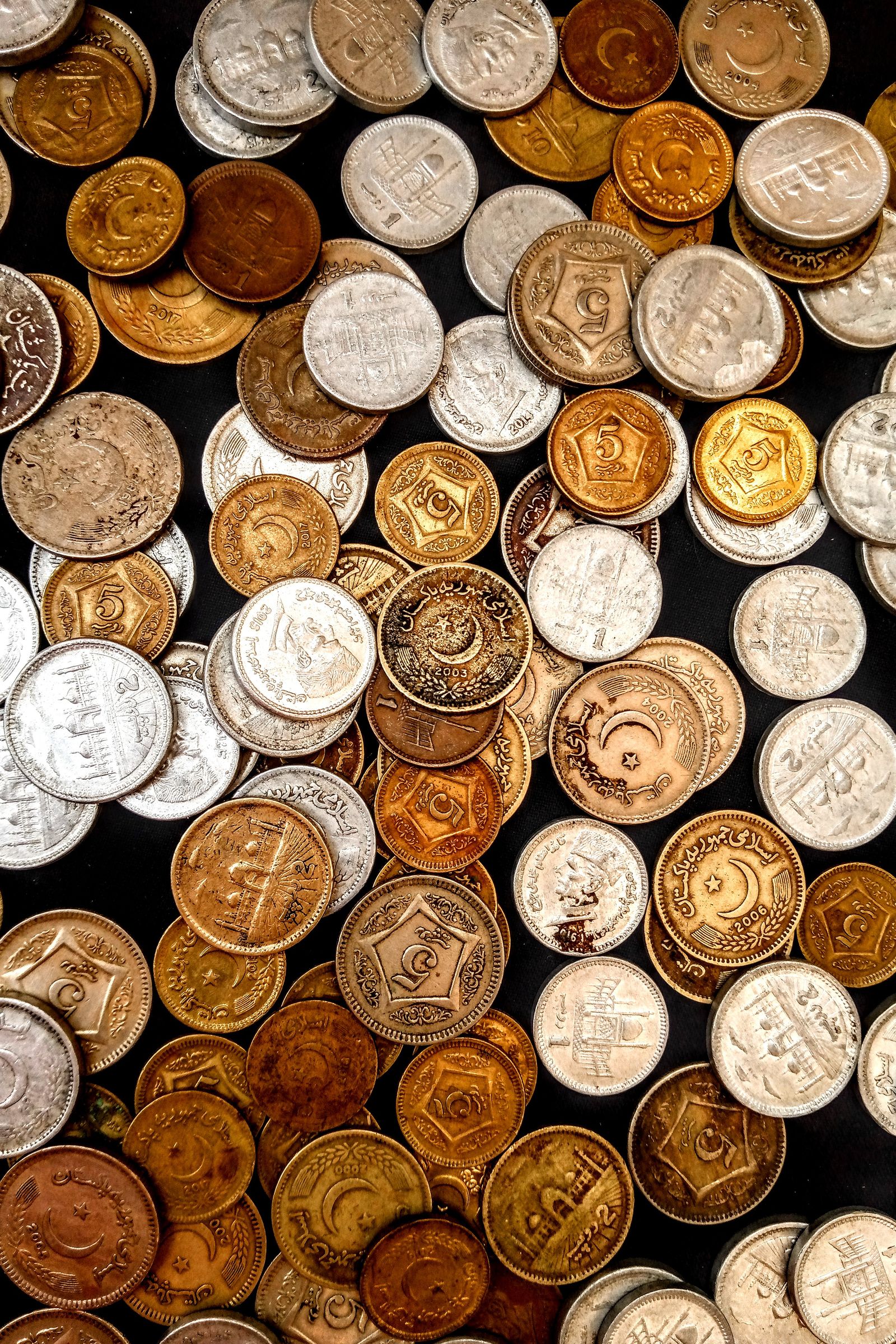 Circulated coins of different years and denominations on a dark surface
